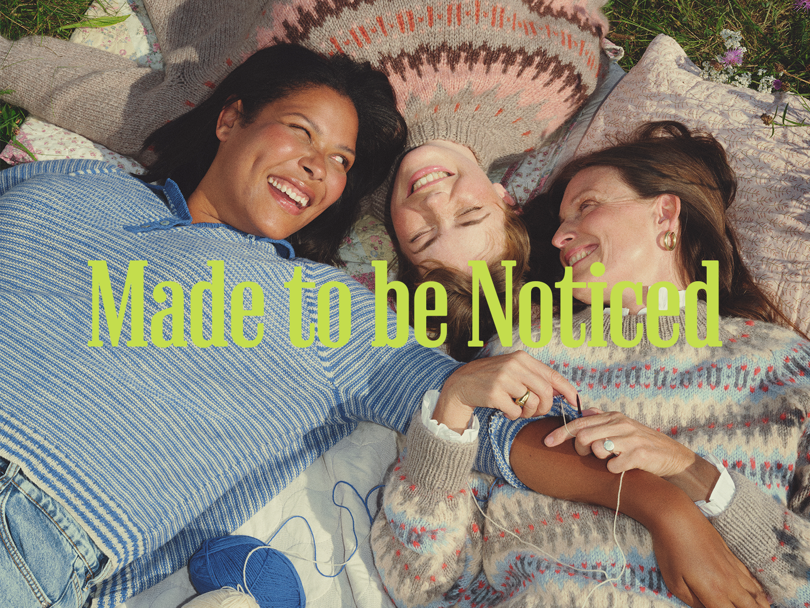 Tre kvinder ligger på et tæppe iført sweatre strikket med Copenhagen Fibers.